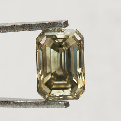 Neutral-background face-up view of the emerald-cut diamond, with bright border facets, dark central reflections and an unobstructed outline.
