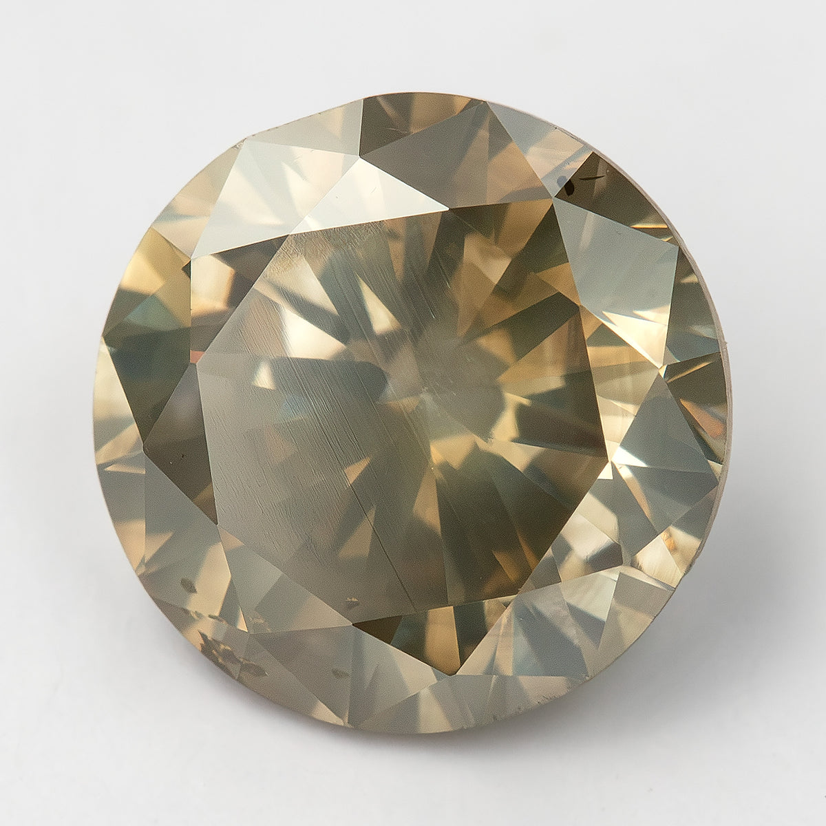 KL444 face-up on a light background, with a pale reflection across part of the table and brown-gray surrounding facets.