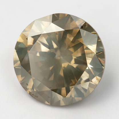 KL444 face-up on a light background, with a pale reflection across part of the table and brown-gray surrounding facets.