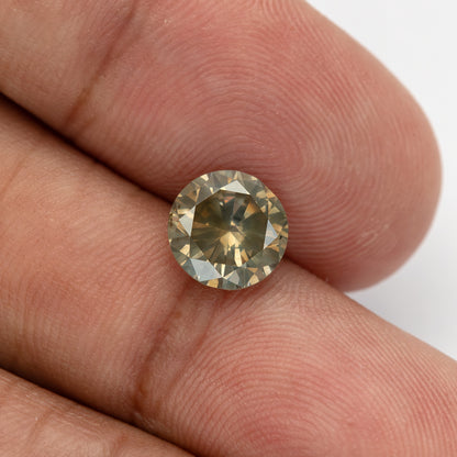 KL444 resting against two fingertips, with a dark central reflection surrounded by brighter crown facets.