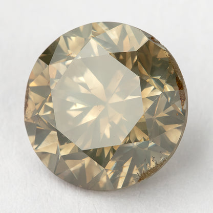 Bright rotated face-up macro of the round brilliant diamond, with a pale champagne center, olive-gray edge reflections and irregular brown features visible along the right and lower girdle.