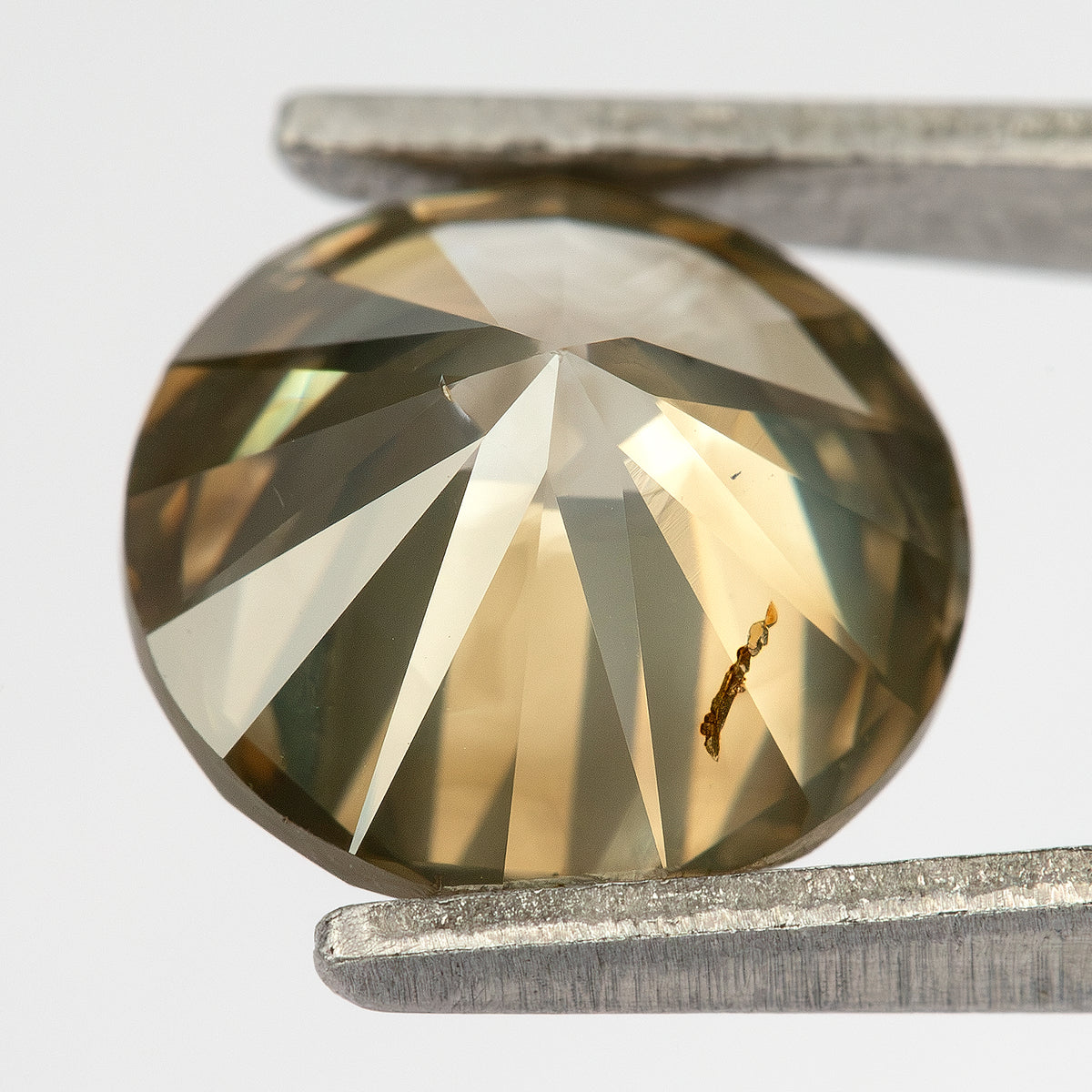 Oblique pavilion and profile macro in tweezers, showing the diamond's depth, culet-side facets and a prominent elongated brown feature across a pavilion facet.