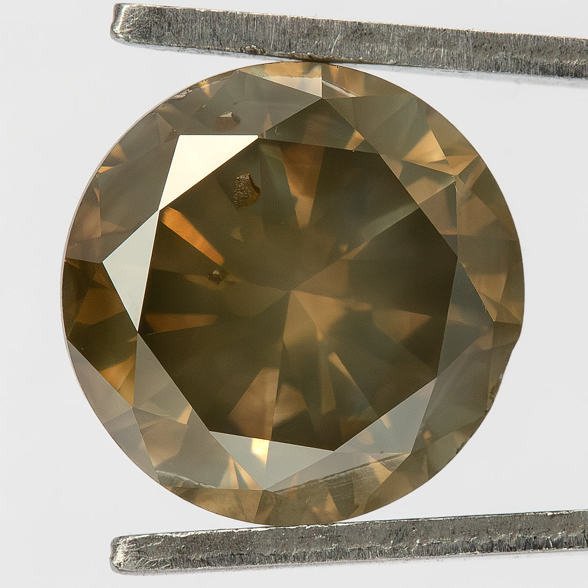 Diamante exacto de 2.01 ct, marrón oliva, brillante redondo, sin tratar, visto desde arriba y sostenido con pinzas, con destellos dorados y una inclusión marrón bajo la zona superior izquierda de la tabla.