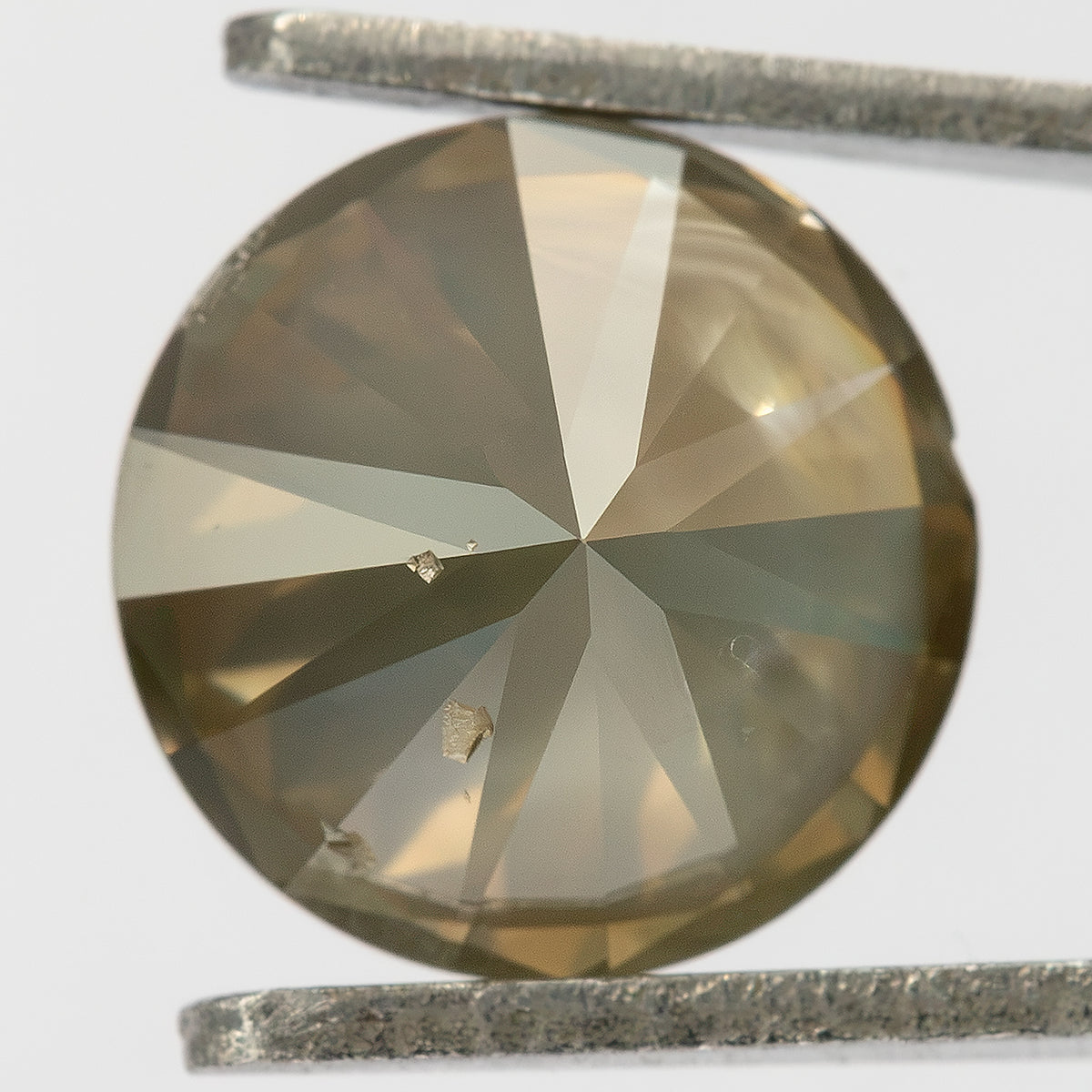 Vista macro del pabellón del diamante exacto de 2.01 ct, marrón oliva, brillante redondo, mostrando facetas radiales e inclusiones pálidas y oscuras en la mitad inferior.