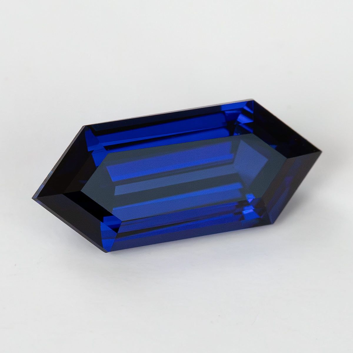 Tilted crown view of the blue hexagonal sapphire with a broad pale table reflection and blue steps around it.