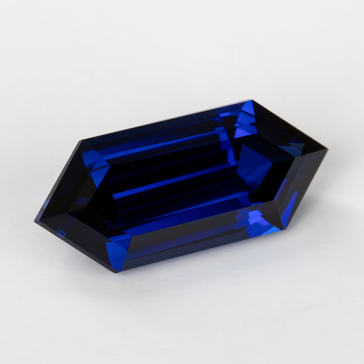 Angled face-up view of the elongated blue sapphire, showing pointed ends and bright blue bands within darker facets.