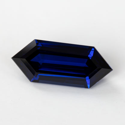 Low angled face-up view showing long blue step facets and the hexagonal outline against a light background.