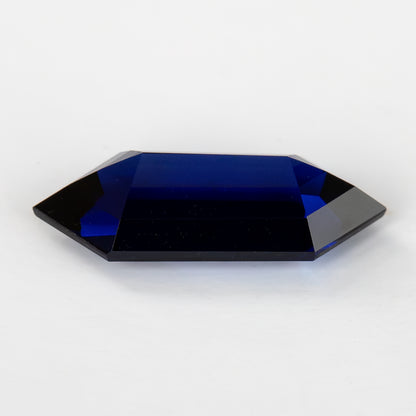 Low side view of the blue sapphire showing its pavilion-side profile and depth, not a face-up presentation.