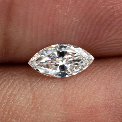 One marquise diamond resting horizontally between fingertips, with skin texture showing the scale of the representative stone.
