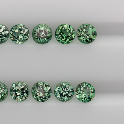Close table-up rows of mint-green round lab-grown sapphires with alternating pale and dark facet reflections.