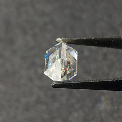 Pavilion side of a faceted hexagon cut gemstone held in tweezers displaying underside facet arrangement.