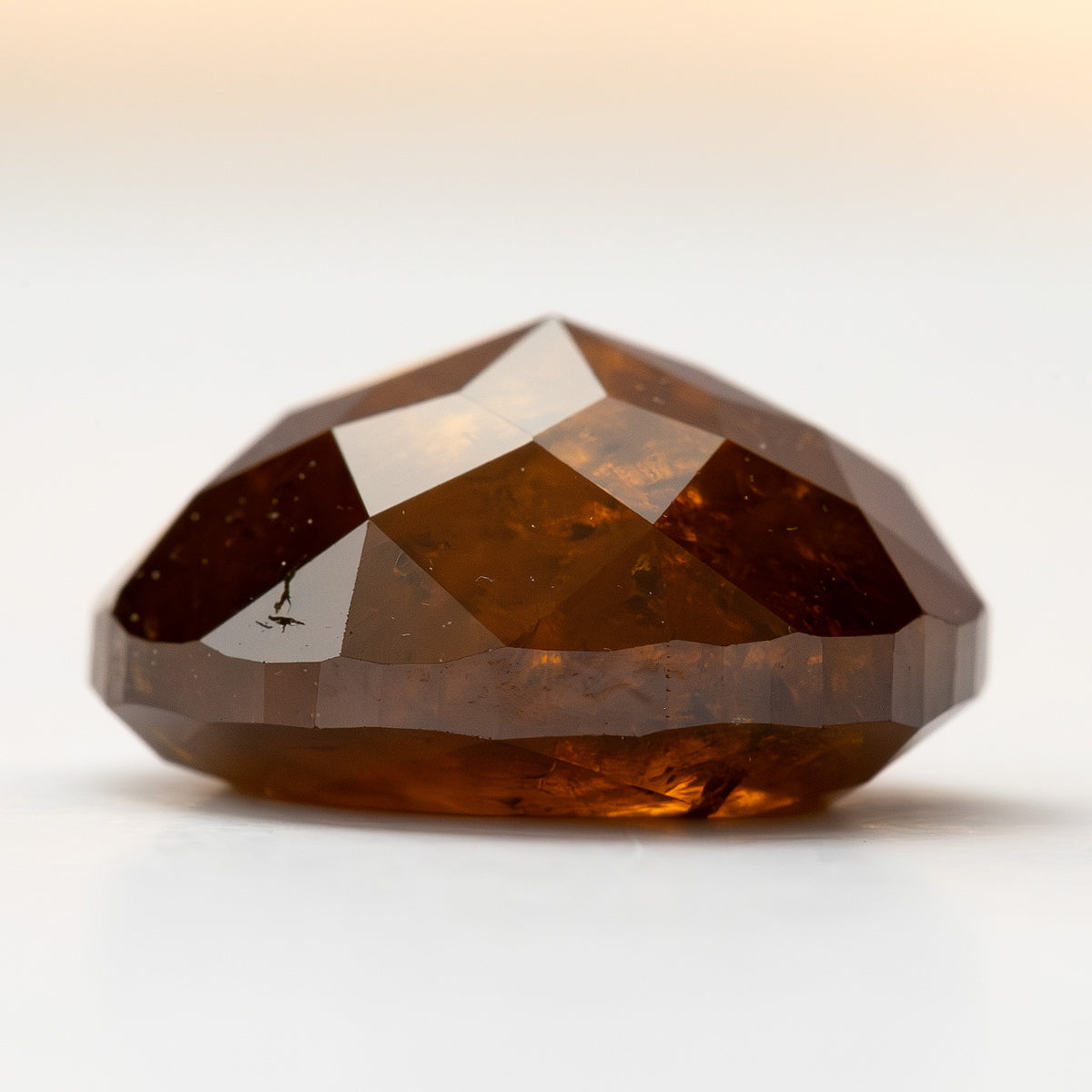 Side profile of the oval stone on white, showing its depth and double-sided faceting.