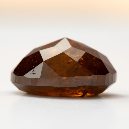 Side profile of the oval stone on white, showing its depth and double-sided faceting.