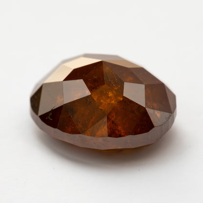 Second low angled loose view of the oval stone on white with bright upper-facet reflections.
