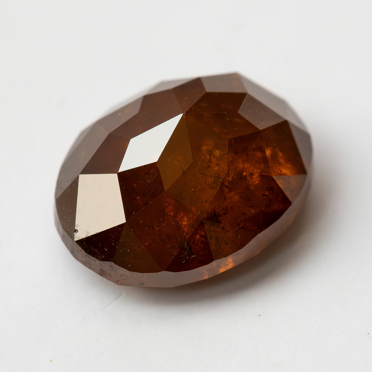 Oblique loose view of the oval stone on white, showing the transition between the two faceted sides.
