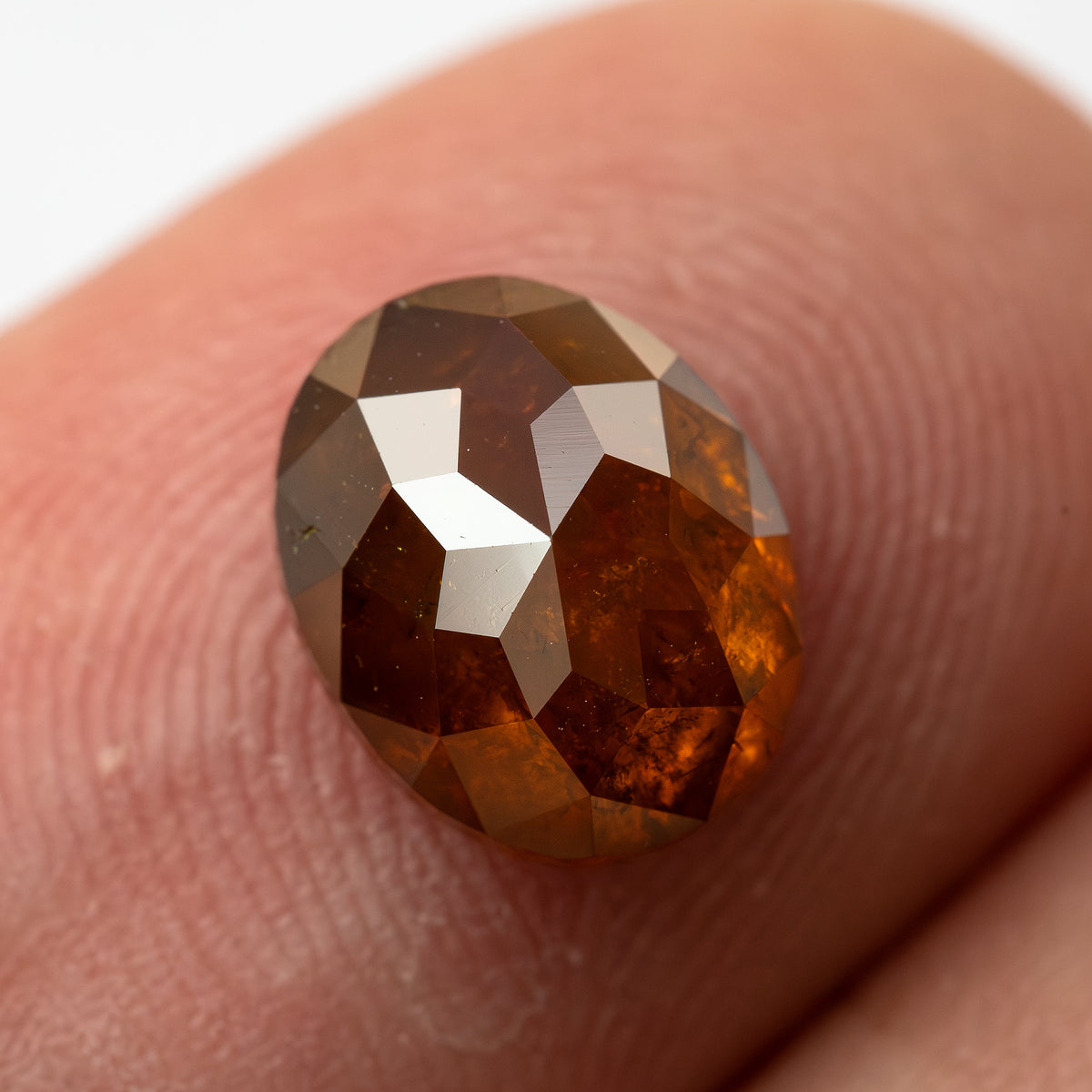 Second face-up fingertip view of the oval stone, showing a different pattern of bright and dark facets.