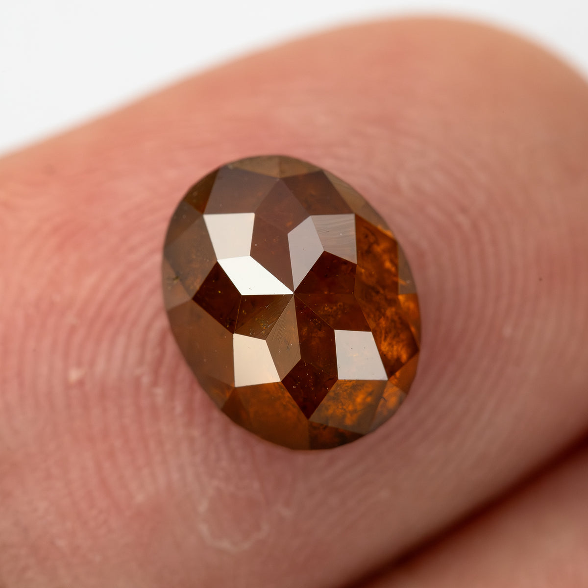 Angled fingertip view of the oval stone, showing its outline and internal pattern.