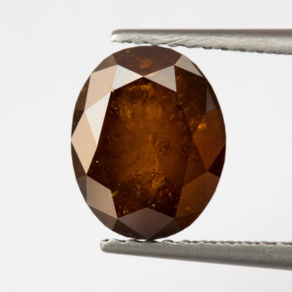 Opposite-side tweezer view of the oval stone, showing a broader central facet field.