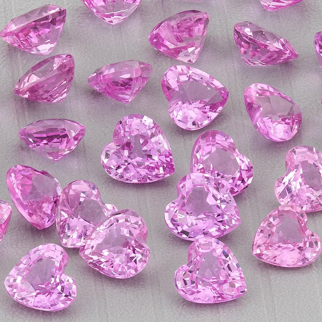 Close-up of a representative parcel of pink heart-shaped sapphires on gray, with face-up hearts and side views; purchase includes five selected stones.