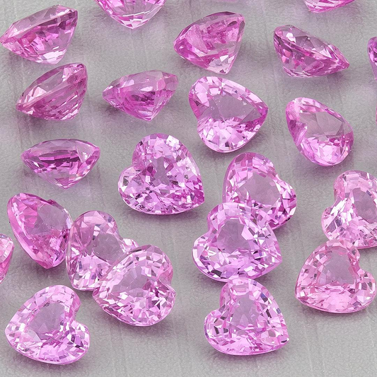 Close-up of a representative parcel of pink heart-shaped sapphires on gray, with face-up hearts and side views; purchase includes five selected stones.