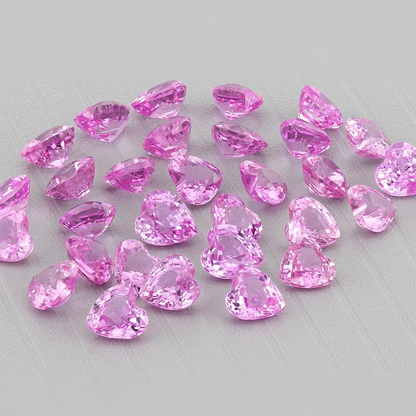 Representative pink heart sapphire parcel grouped on a gray surface, with space around the stones; five sapphires are selected per purchase.