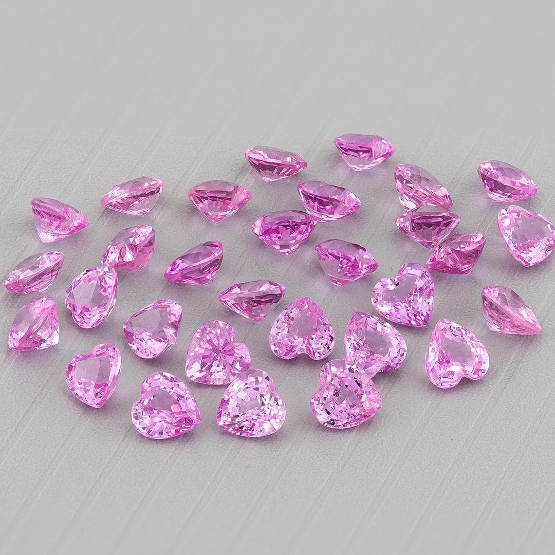 Pink heart-shaped sapphires grouped on gray, showing the representative parcel from a slightly different angle.