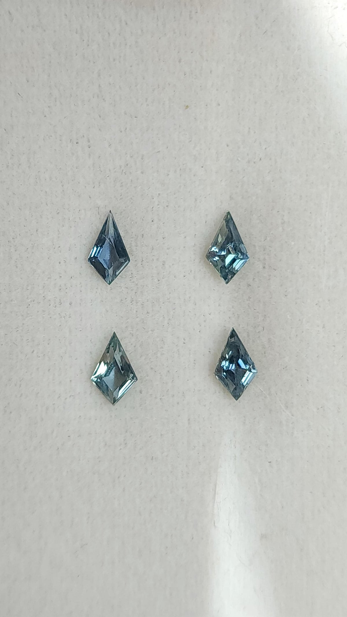 Four kite-shaped teal sapphires viewed face-up. View 2.