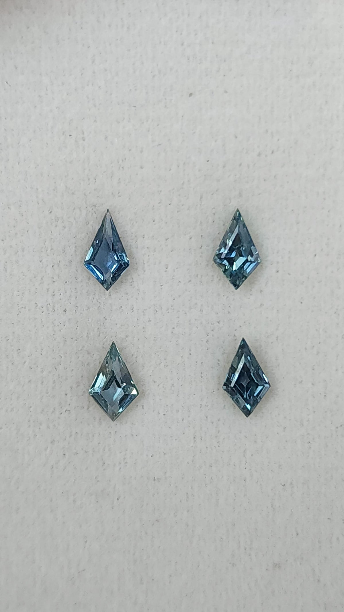 Four kite-shaped teal sapphires viewed face-up. View 7.