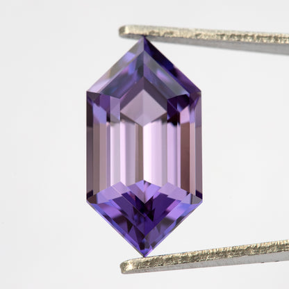 Zafiro hexagonal violeta púrpura visto desde arriba en pinzas con reflejos más claros a través de las facetas escalonadas centrales.