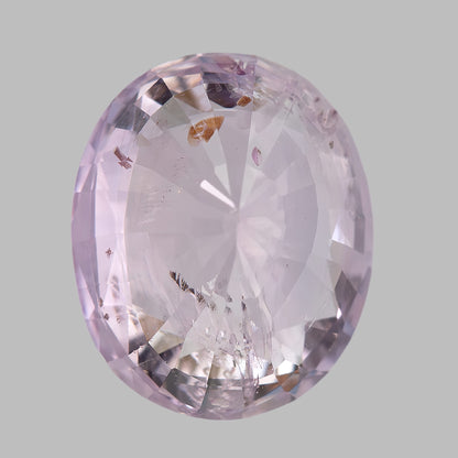 Reverse view of the pink oval sapphire with its long axis upright, showing pale reflections and brown inclusion patches.