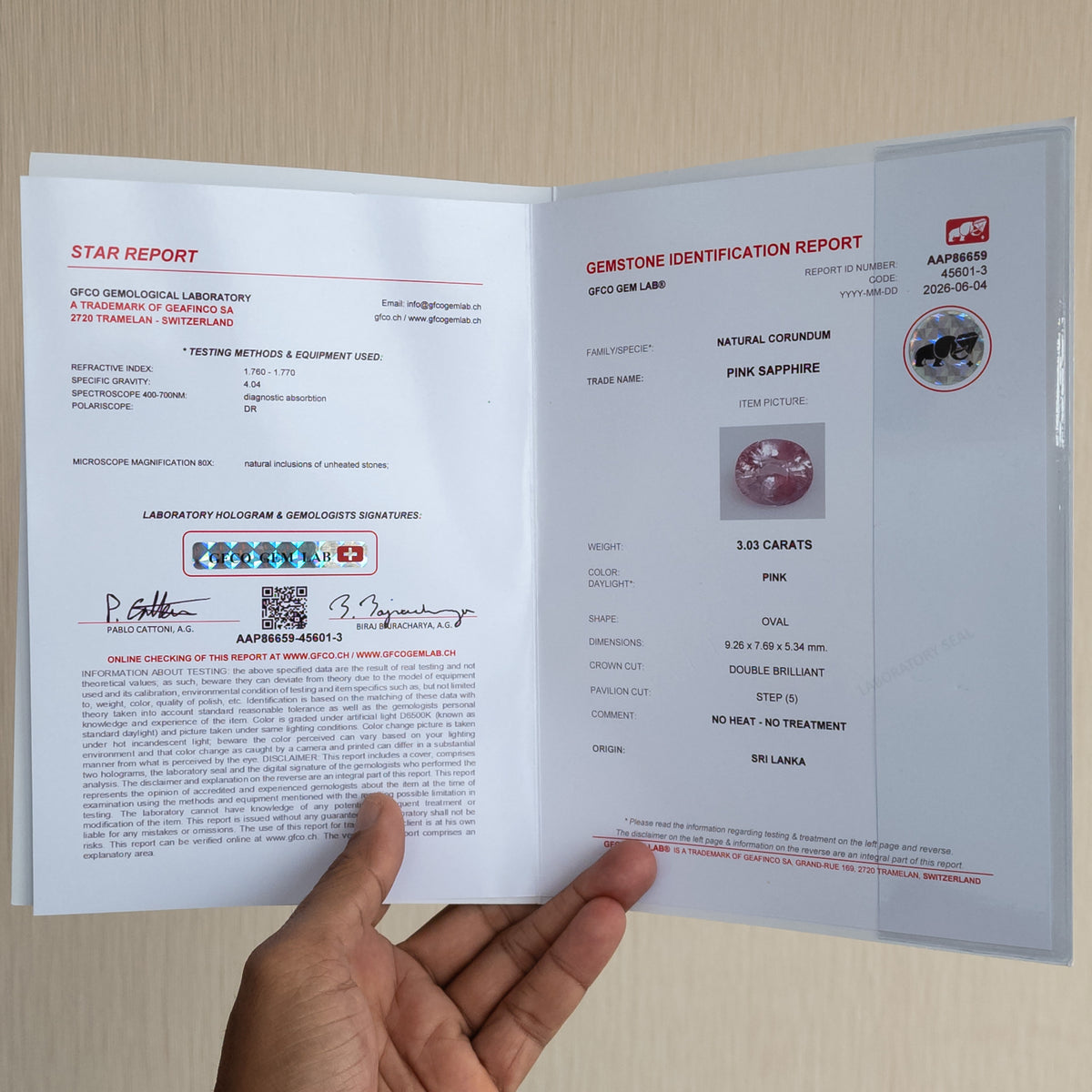 Open GFCO gemstone identification report booklet for the pink sapphire, photographed in a hand.