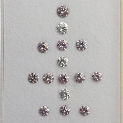 Face-up arrangement of twelve purple-pink diamonds with three white comparison diamonds on a white surface.
