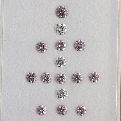 Alternate face-up arrangement of twelve purple-pink diamonds with three white comparison diamonds on a white surface.