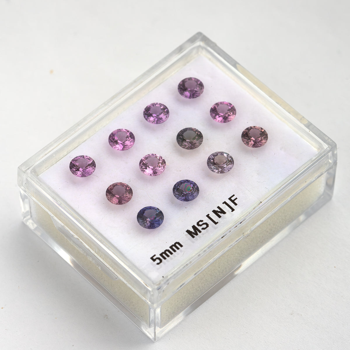 プラスチック製のディスプレイボックスに入った、12個のラウンドファセットカットサファイアを斜めから見た様子。