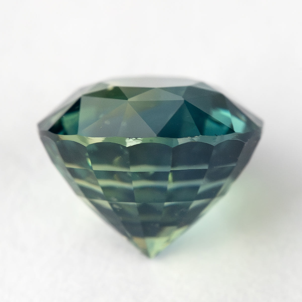 Side profile of the deep teal blue green sapphire showing its depth and pavilion facets.