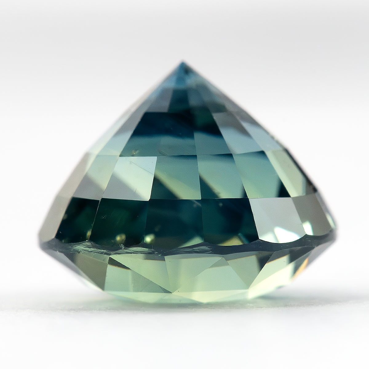 Inverted side profile of the round teal-blue and green sapphire resting on its table, with its pointed pavilion facing upward.