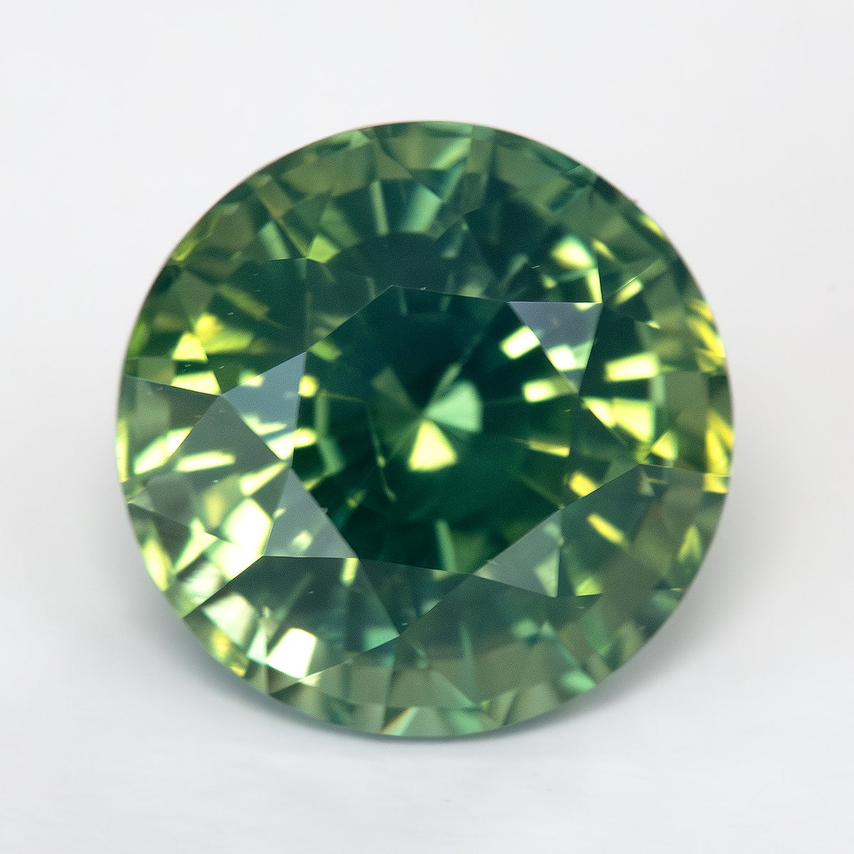 Face-up view of round olive teal green sapphire, high contrast.