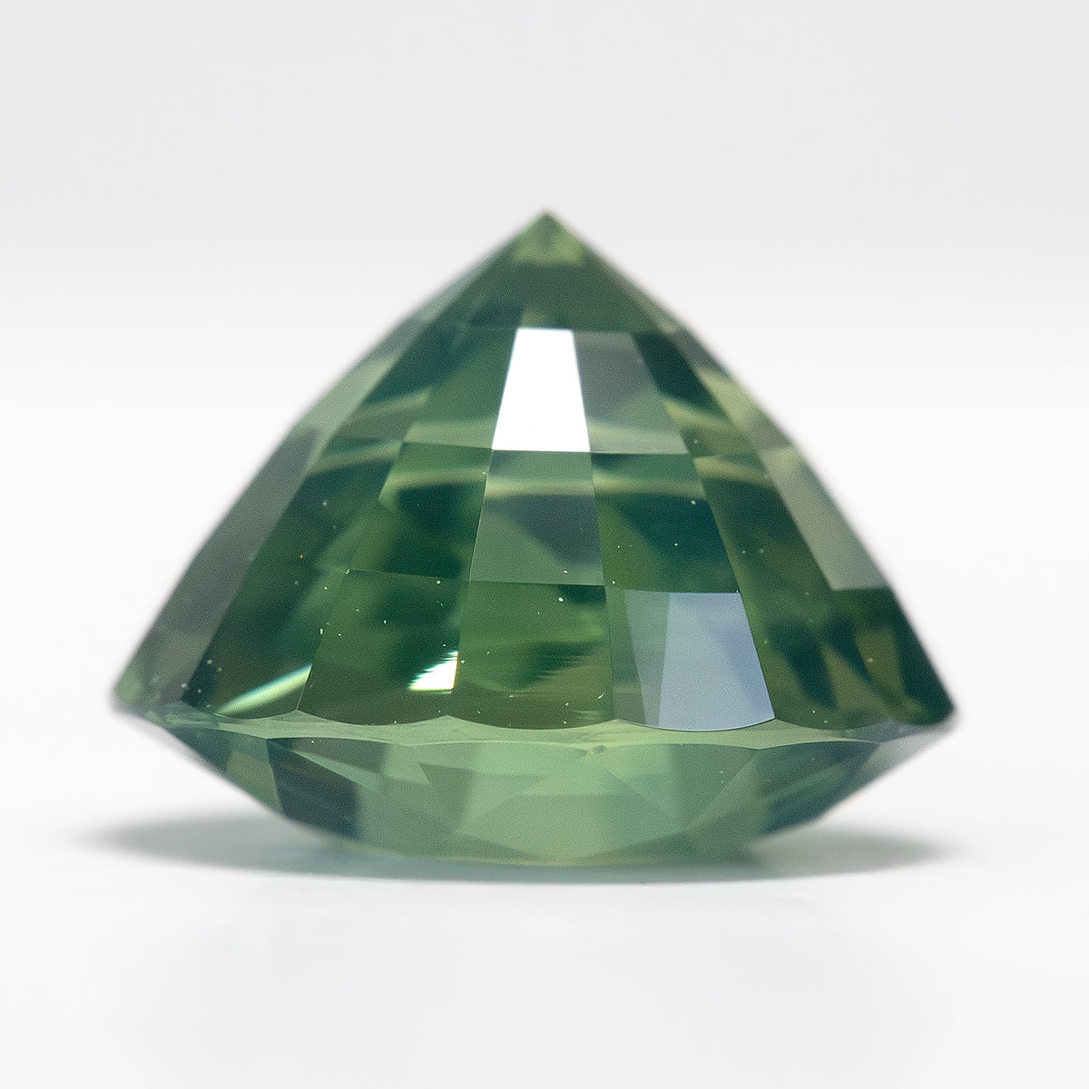Side profile of the deep olive teal green sapphire showing its depth and pavilion facets.