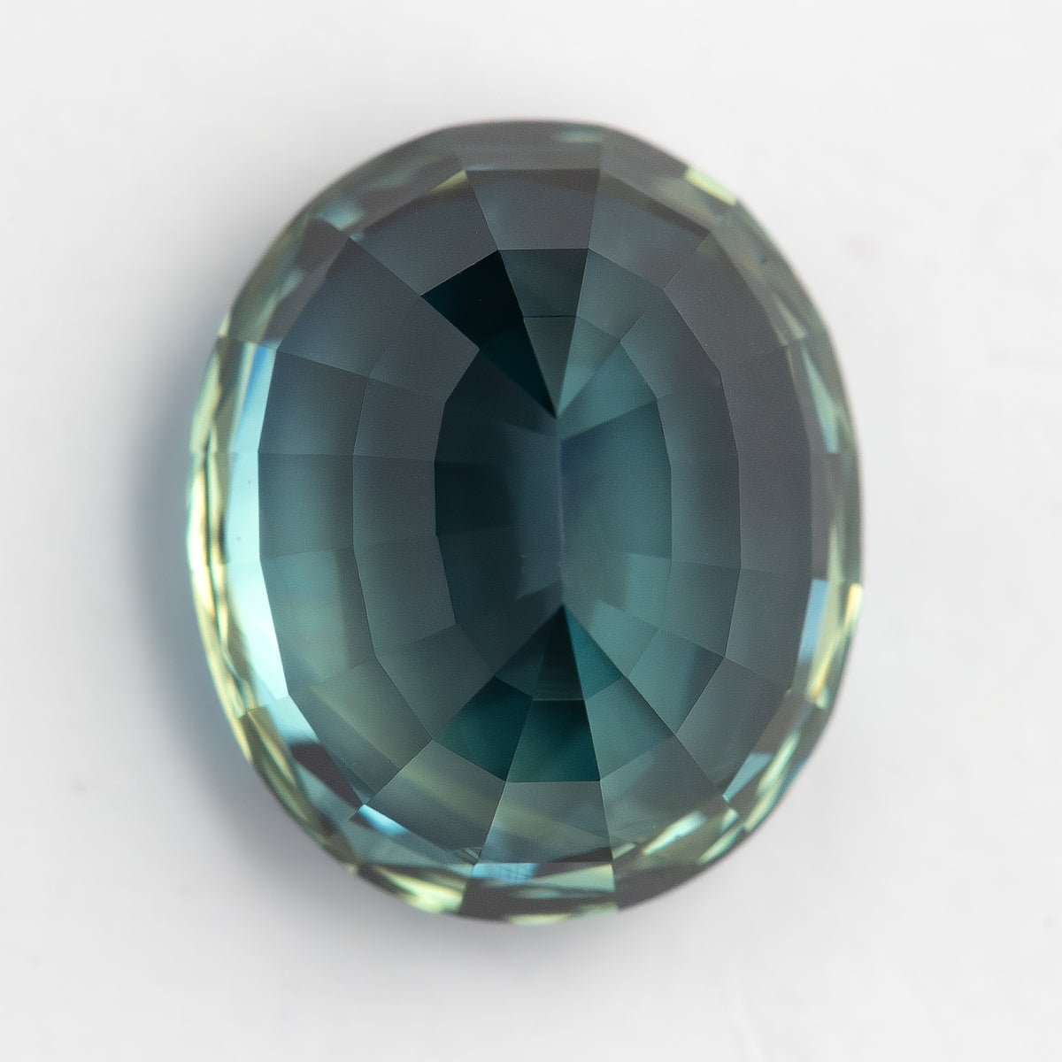 Pavilion-side view of the oval sapphire on white, with a pale blue-green centre and darker perimeter.
