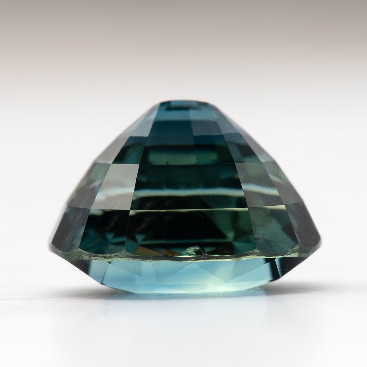 Side profile of the oval sapphire resting on white, showing crown height and pavilion depth.