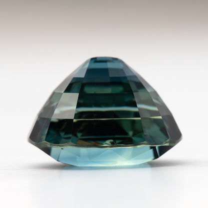 Side profile of the oval sapphire resting on white, showing crown height and pavilion depth.