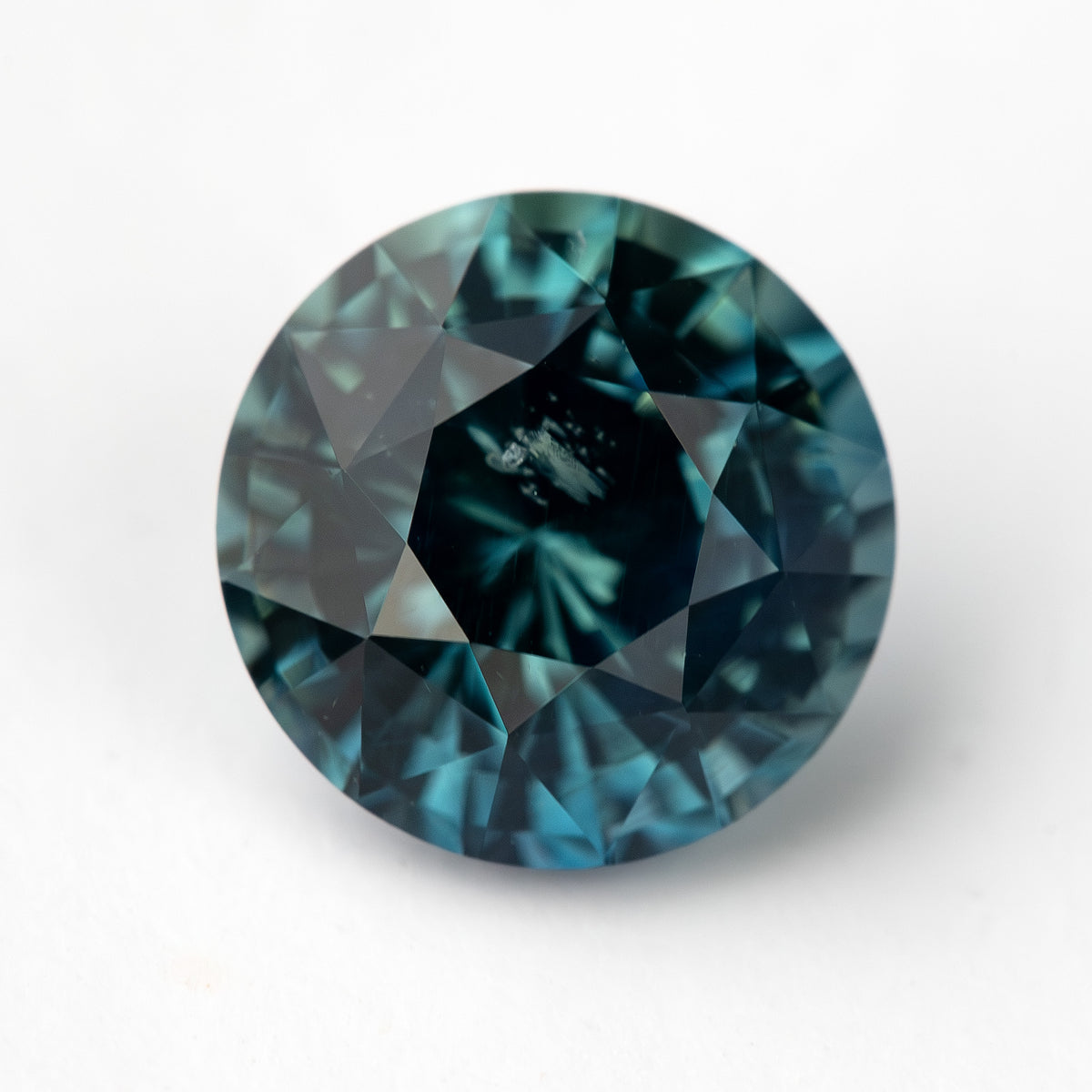Round deep teal blue-green sapphire shown face-up on a white background.