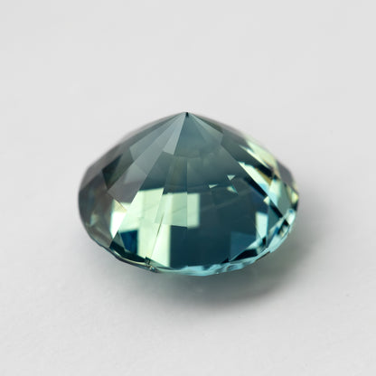 Teal blue-green round step-cut sapphire shown at an angle from the pavilion side. View 12.