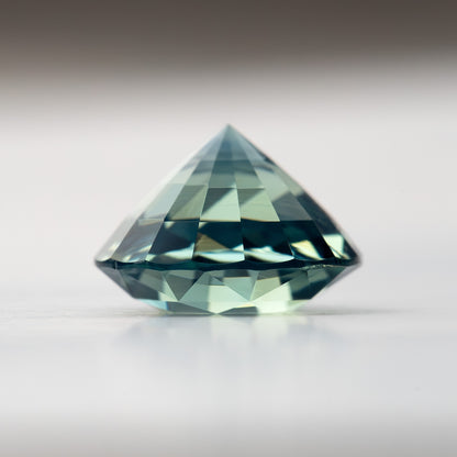 Teal blue-green round step-cut sapphire viewed from the side, showing crown and pavilion depth. View 14.