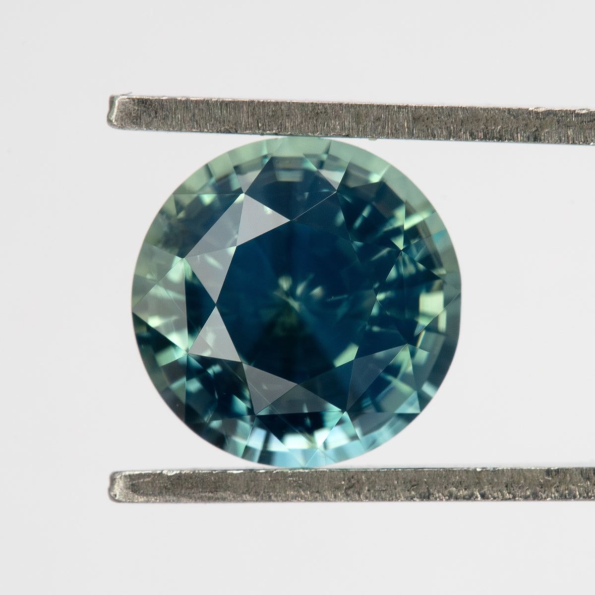Teal blue-green round step-cut sapphire viewed face-up. View 2.