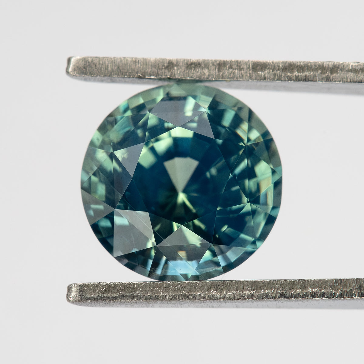 Teal blue-green round step-cut sapphire viewed face-up. View 10.