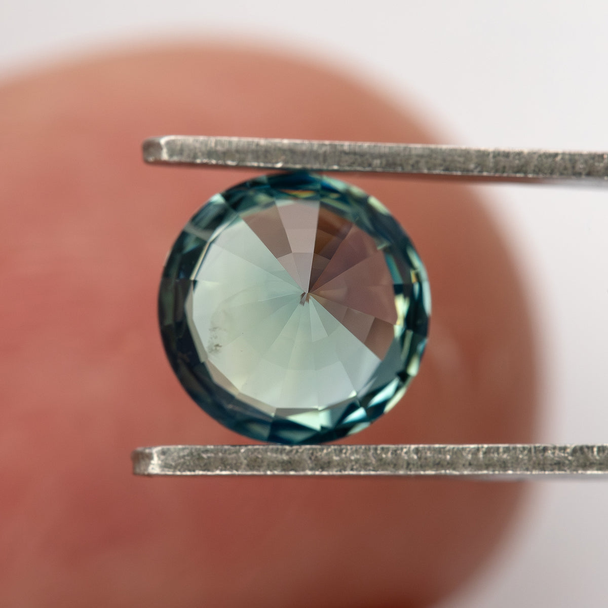 Teal blue-green round step-cut sapphire viewed from the pavilion side. View 15.