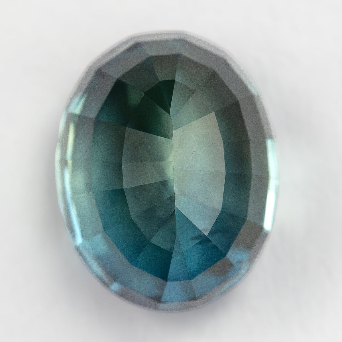 Reverse view of the oval sapphire showing pavilion facets on a pale background.