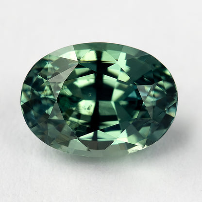 Teal-green oval sapphire in a second face-up orientation, showing contrasting dark and bright facets.