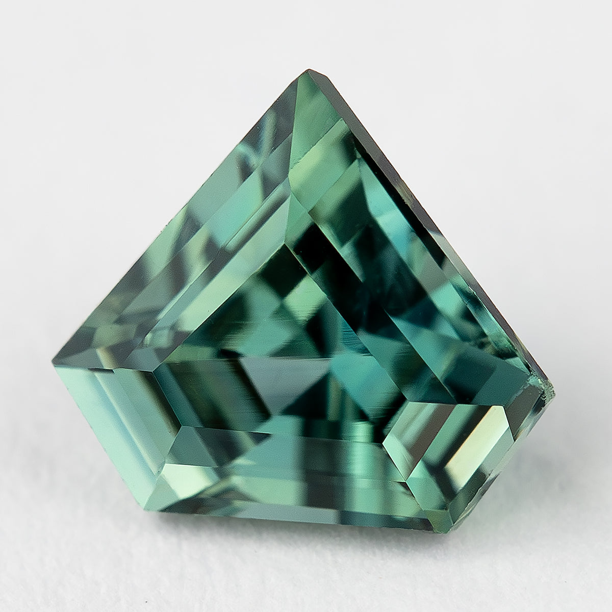 Three-quarter face-up view of the loose shield sapphire, showing the angled sides and facet pattern.